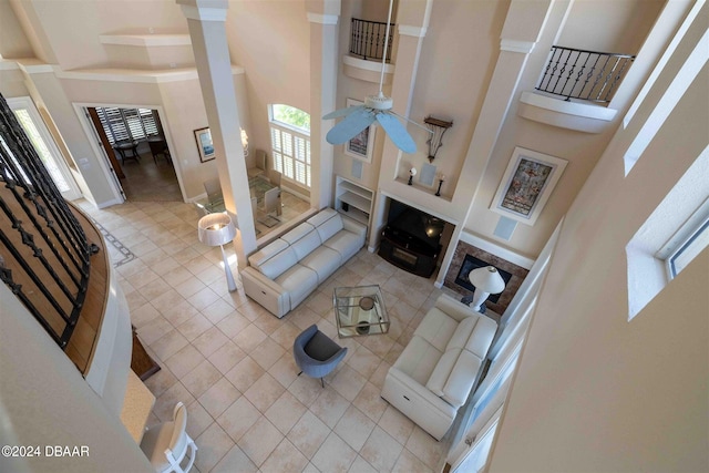 living room featuring light tile patterned flooring, ceiling fan, and a towering ceiling