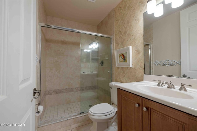 bathroom featuring toilet, vanity, tile patterned flooring, and a shower with door