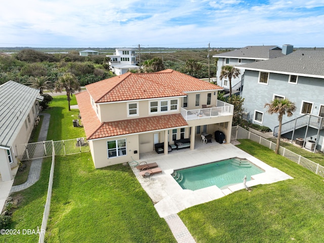 back of property featuring a balcony, a lawn, a fenced in pool, and a patio