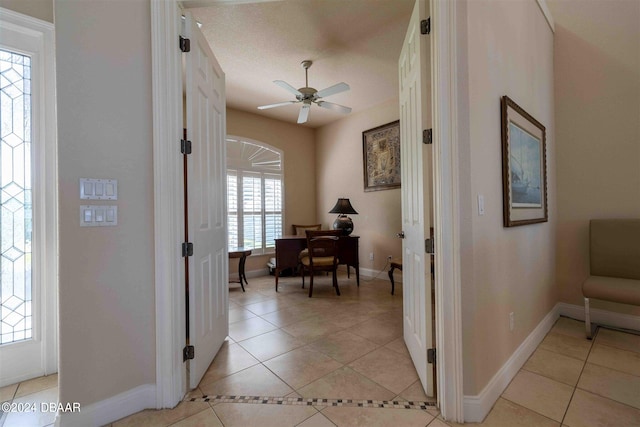 hall featuring light tile patterned flooring, plenty of natural light, and a textured ceiling