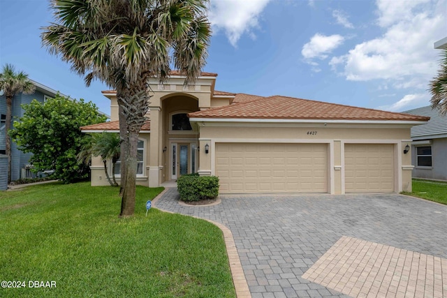 mediterranean / spanish house with a garage and a front lawn