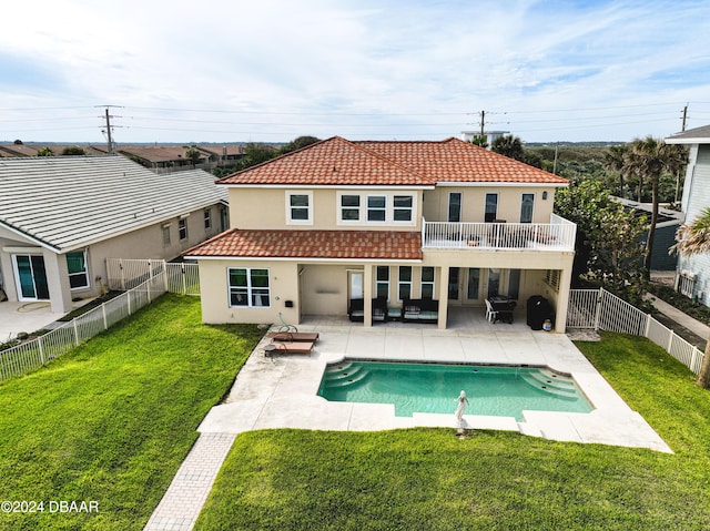 rear view of house featuring a balcony, a lawn, a fenced in pool, and a patio area