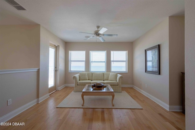 living room featuring ceiling fan, a textured ceiling, and light hardwood / wood-style flooring