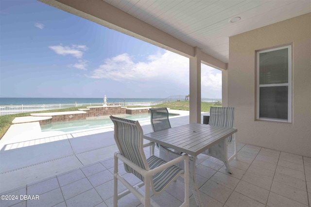 view of patio / terrace with a swimming pool with hot tub, a water view, and pool water feature