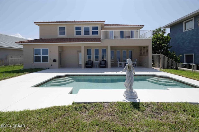 back of property with a fenced in pool, a patio area, french doors, and a balcony