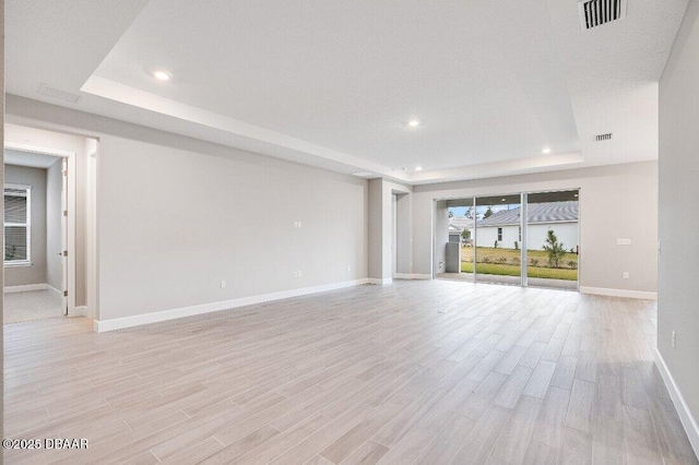 unfurnished living room with a raised ceiling and light hardwood / wood-style flooring