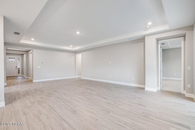 unfurnished room featuring a tray ceiling and light hardwood / wood-style floors