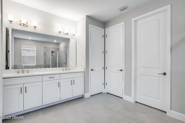 bathroom featuring tile patterned flooring, vanity, an enclosed shower, and a textured ceiling