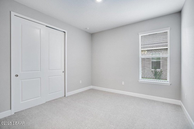 unfurnished bedroom with light carpet and a closet