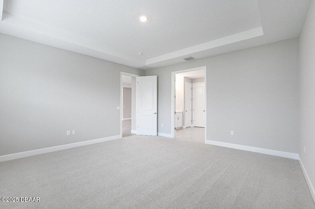 carpeted empty room with a raised ceiling and a textured ceiling