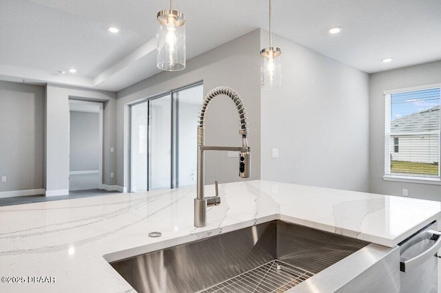 details with pendant lighting, stainless steel dishwasher, sink, and light stone counters