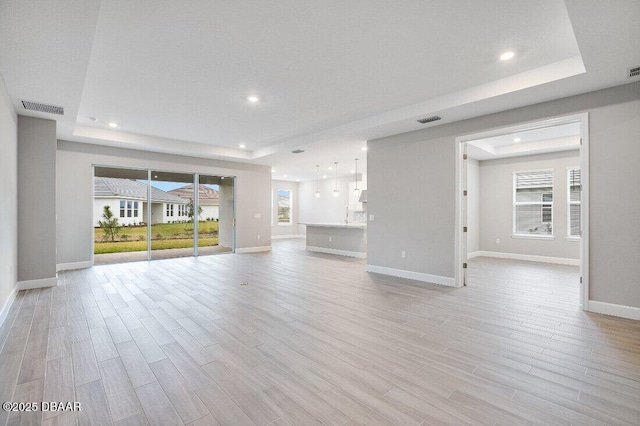 unfurnished living room featuring light hardwood / wood-style floors and a tray ceiling