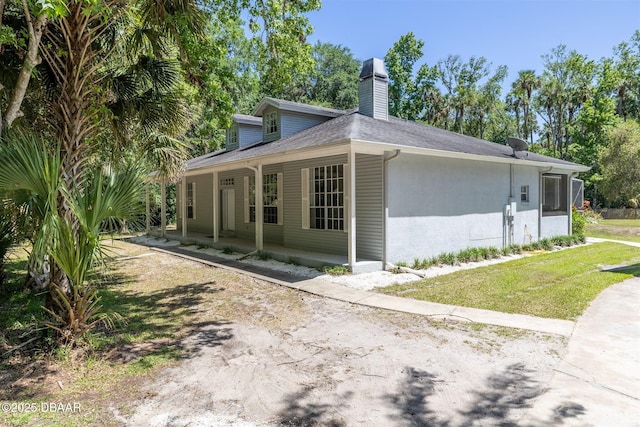 view of home's exterior featuring a chimney and a porch