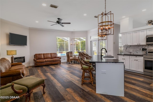 kitchen with a sink, visible vents, open floor plan, dark countertops, and appliances with stainless steel finishes