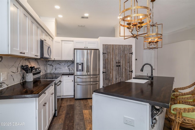 kitchen featuring a sink, an inviting chandelier, decorative backsplash, dark wood-style floors, and appliances with stainless steel finishes