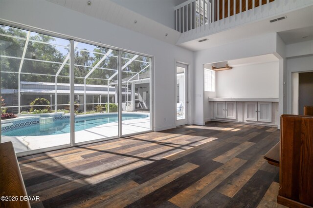 760 Trophy Hunter Trl, New Smyrna Beach, FL 32168 - unfurnished living room featuring a sunroom, baseboards, dark wood-style floors, and visible vents