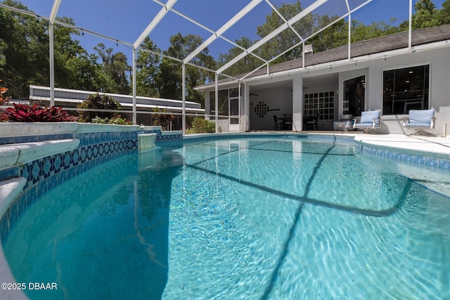 pool with a patio area, a ceiling fan, and glass enclosure