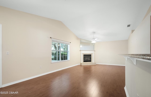 unfurnished living room featuring baseboards, a tile fireplace, ceiling fan, wood finished floors, and vaulted ceiling