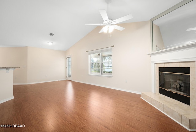 unfurnished living room featuring baseboards, a tiled fireplace, lofted ceiling, ceiling fan, and wood finished floors