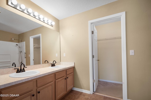 full bath with a spacious closet, a sink, and tile patterned floors