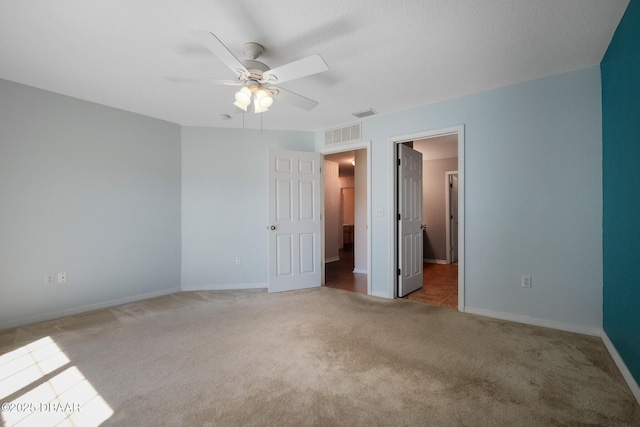 unfurnished bedroom featuring baseboards, visible vents, ceiling fan, and light colored carpet