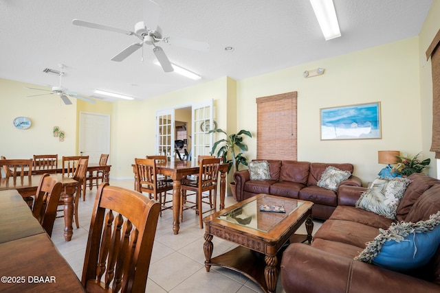 living room with ceiling fan, visible vents, a textured ceiling, and light tile patterned flooring