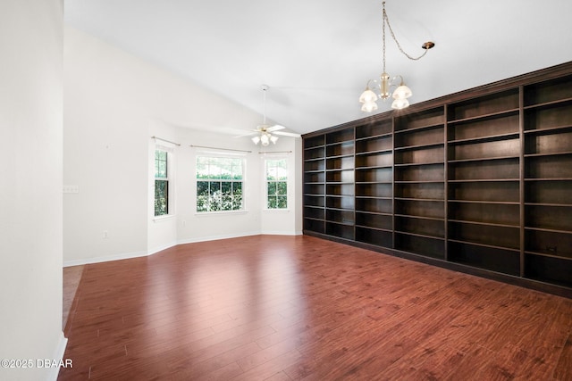 spare room with ceiling fan with notable chandelier, vaulted ceiling, baseboards, and wood finished floors