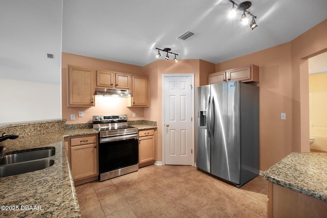 kitchen featuring light stone counters, under cabinet range hood, stainless steel appliances, a sink, and visible vents