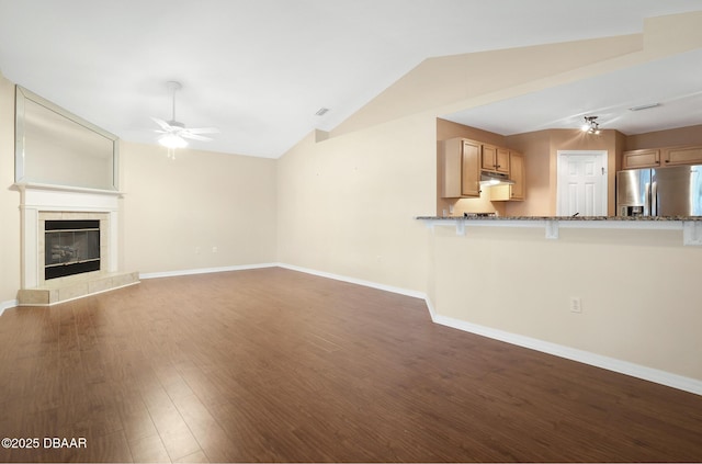 unfurnished living room with baseboards, a ceiling fan, wood finished floors, vaulted ceiling, and a fireplace