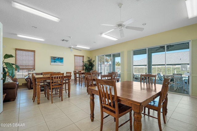 dining room featuring light tile patterned floors, ceiling fan, visible vents, and a textured ceiling