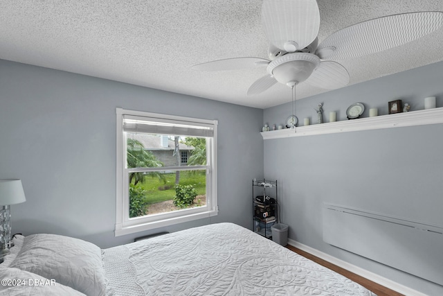 bedroom featuring ceiling fan, a textured ceiling, and wood-type flooring