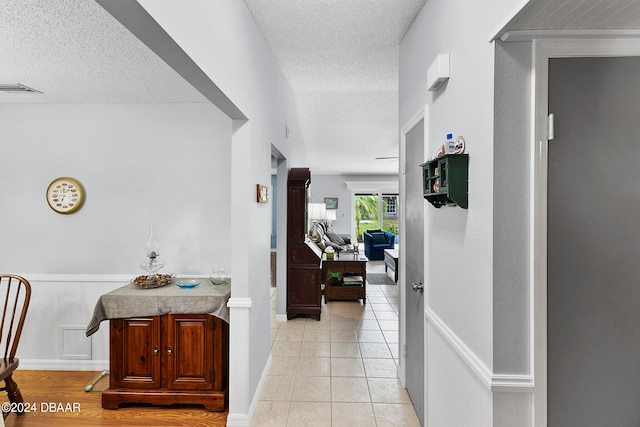 hallway featuring light tile patterned flooring and a textured ceiling