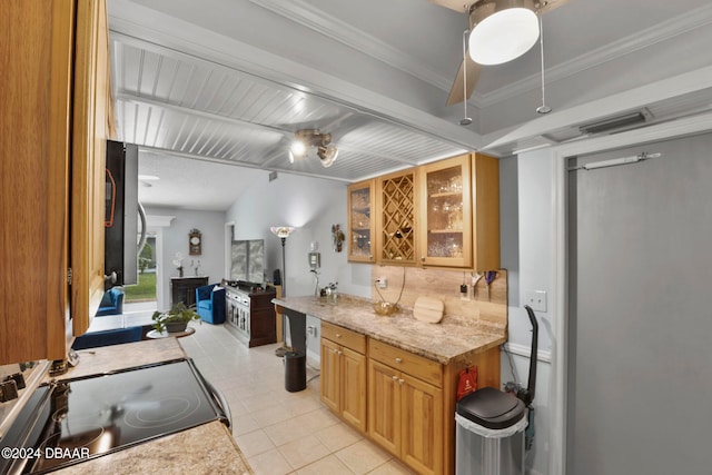 kitchen with stove, light stone counters, light tile patterned floors, and crown molding