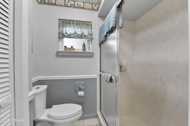 bathroom with tile patterned flooring, toilet, and a shower with door