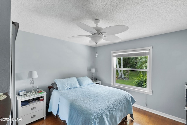 bedroom with a textured ceiling, ceiling fan, and dark hardwood / wood-style floors