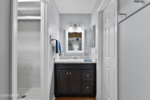 bathroom featuring vanity, an enclosed shower, and a textured ceiling