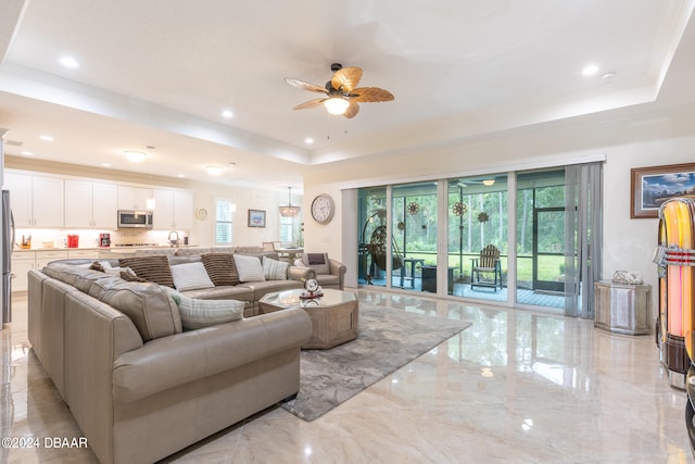 living room featuring a tray ceiling, sink, and ceiling fan