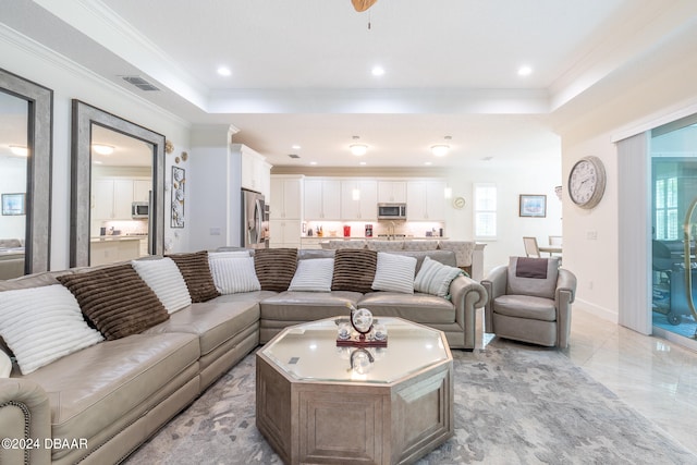 living room featuring a tray ceiling and ornamental molding