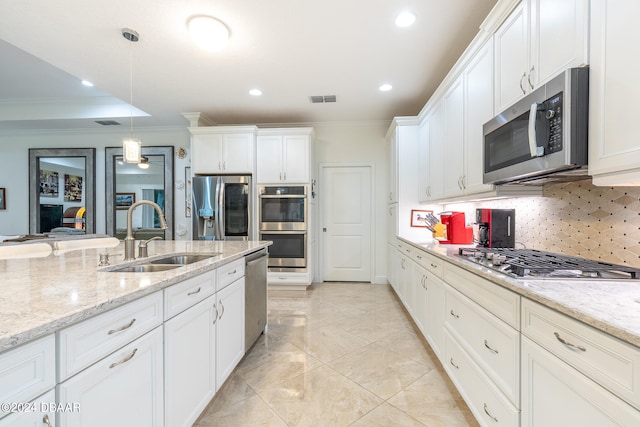 kitchen featuring decorative backsplash, hanging light fixtures, sink, white cabinetry, and appliances with stainless steel finishes