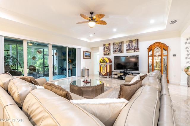 living room featuring a tray ceiling, ceiling fan, and crown molding