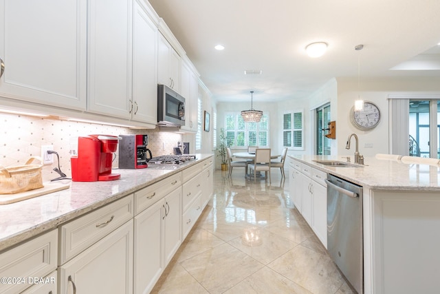 1124 Sea Shell Ct, Daytona Beach, FL 32124 - kitchen featuring stainless steel appliances, a sink, backsplash, white cabinetry, and hanging light fixtures