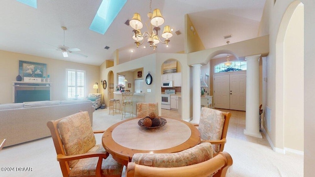 tiled dining area with ornate columns, high vaulted ceiling, and ceiling fan with notable chandelier