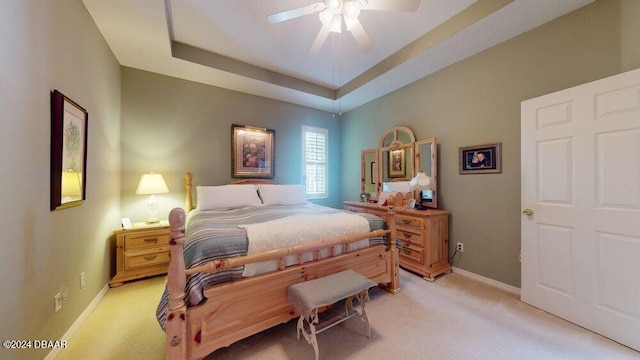 bedroom featuring light carpet, ceiling fan, and a raised ceiling