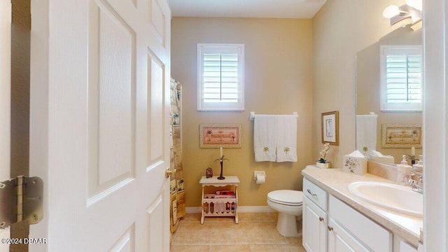 bathroom featuring toilet, vanity, a wealth of natural light, and tile patterned floors