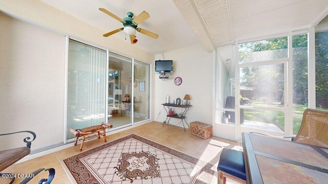 sunroom / solarium featuring beamed ceiling and ceiling fan