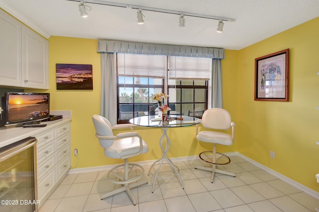 tiled dining area featuring rail lighting and wine cooler