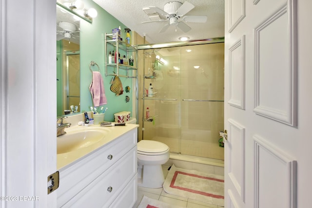 bathroom featuring toilet, tile patterned flooring, a textured ceiling, an enclosed shower, and vanity