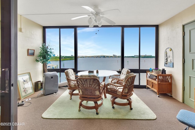 dining space with expansive windows, ceiling fan, a water view, and carpet