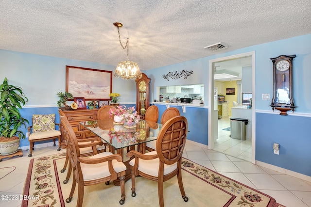 dining space featuring a textured ceiling, a notable chandelier, and light tile patterned floors