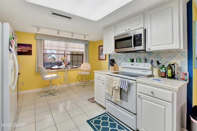 kitchen featuring rail lighting, light tile patterned floors, backsplash, white appliances, and white cabinets